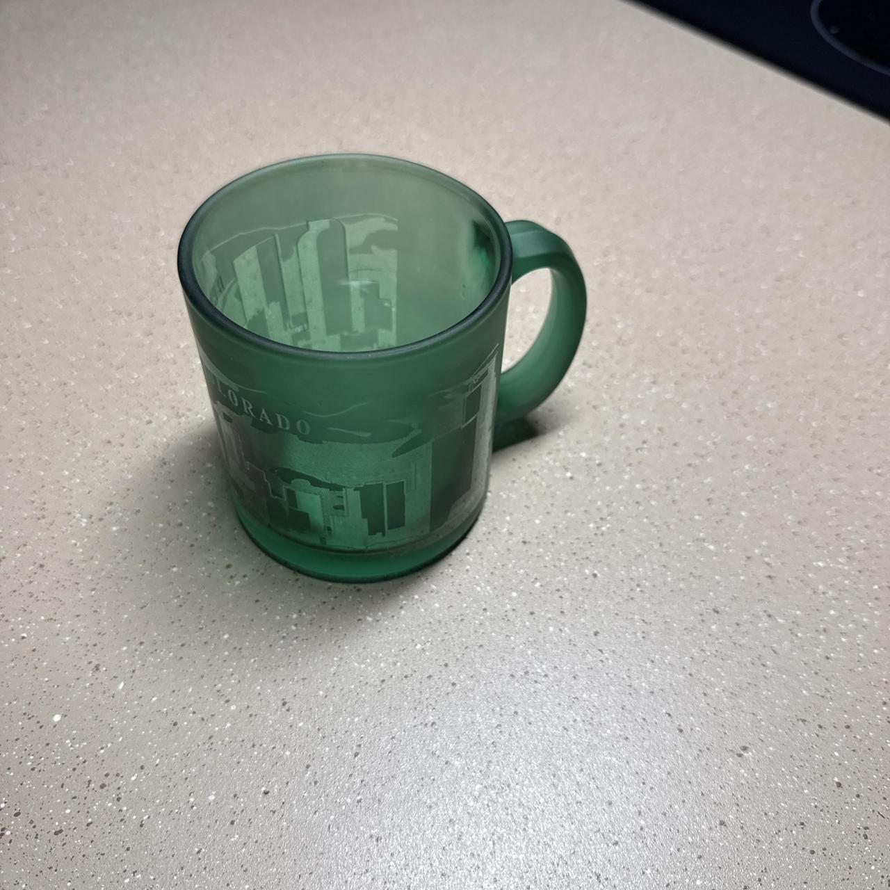 Green glass mug with white cityscape graphic and...